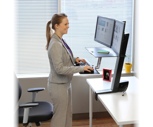 Ergotron WorkFit-S Dual, Black Colour, Side View, Raised Workstation, Office Usage, Person Typing, Woman Standing, Keyboard, Mouse, Two Monitors